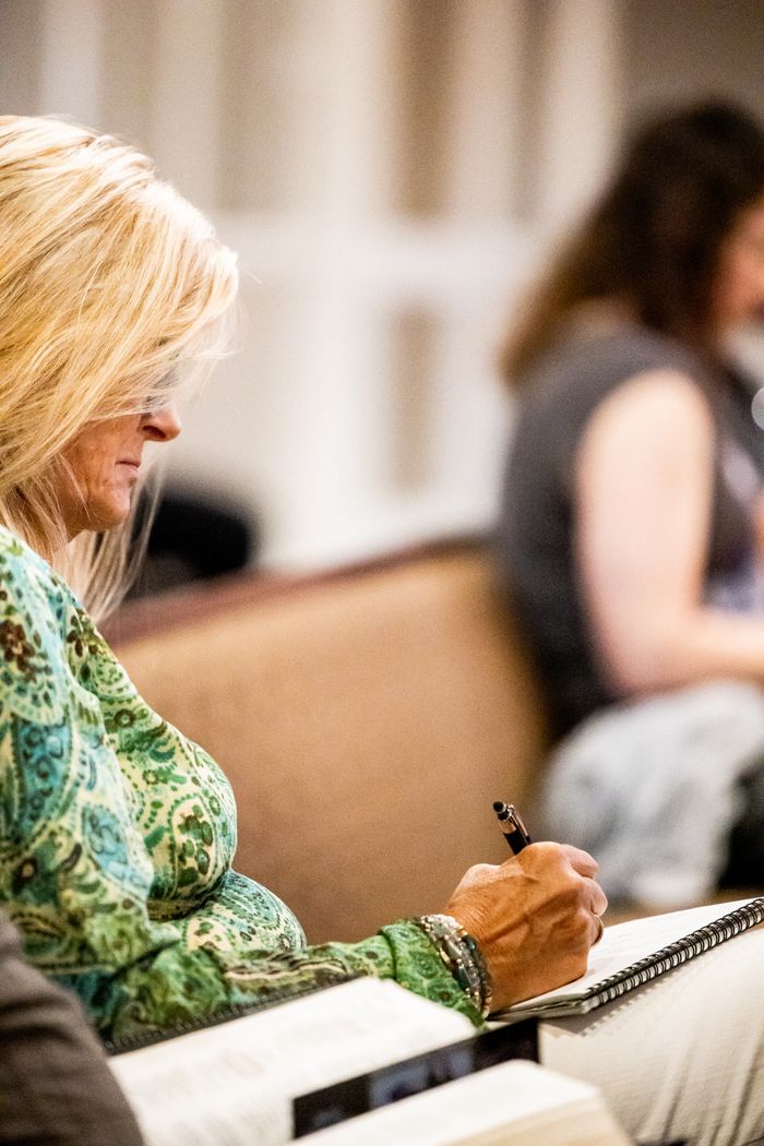 Mastering the First Impression: Your intriguing post title goes here A woman attentively taking notes during a class, emphasizing focus and concentration.